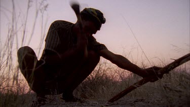 bushmen sharpening spear with crude axe