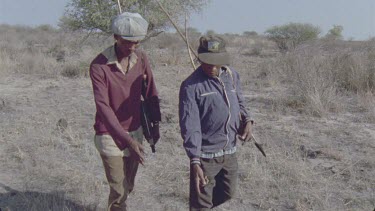bushmen hunters tracking animal through bush looking for spoor with bows and arrows