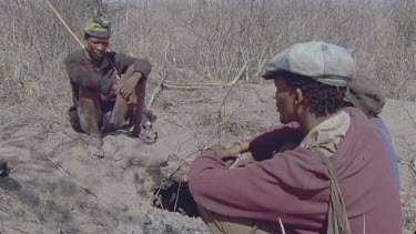 Bushmen three sitting around hole in ground warthog hole