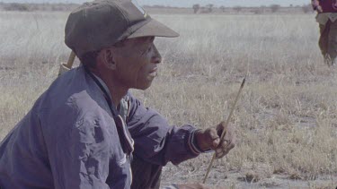 one bushman with his arrow in FG two more join him and squat beside