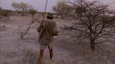 bushman tracking prey preparing to shoot with bow and arrow testing wind direction then firing