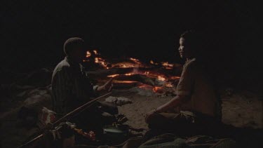 bushmen playing hand clapping game in front t of campfire