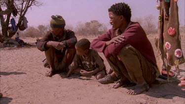 bushman baby tracks in sand while family watches
