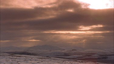 clouds blowing over snow topped mountains