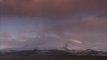 clouds blowing over snowy mountains in distance