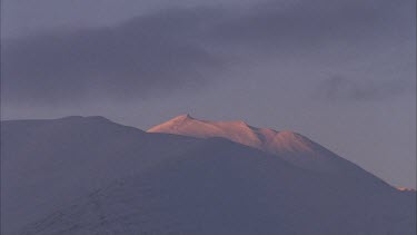 snow covered mountain with sun casting light on the peak