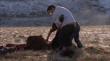 Inuit hunters cutting moose into parts, removing legs, skin, head
