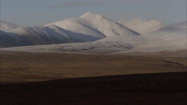 snow capped mountains in tundra landscape.