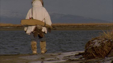 Inuit man walking away from camera, rear view