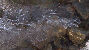 water running beneath the icy slates on top of river