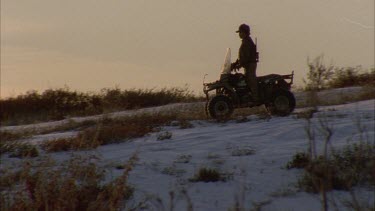 Inuit hunter on buggy drives over hill