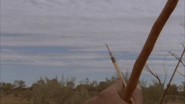 CU of aboriginal man's hand movements as he shoots the arrow