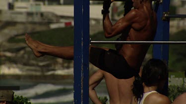 Men doing strength exercises on a pull-up gym at the beach