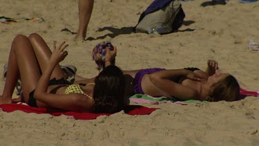 Women in bikinis sunbathing on a beach