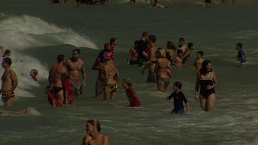 Vacationers wading in the water on a crowded beach