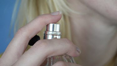 Hands; lady sprays perfumes on her neck