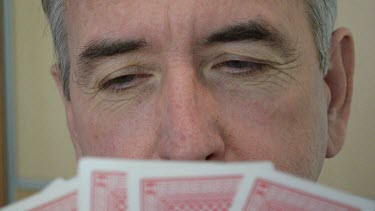 Man's face half covered with palying cards.
