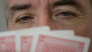 man's eyes half covered with palying cards.
