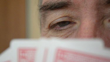 of the man eyes half covered with palying cards.