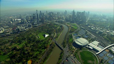 Aerial. Melbourne. City skyline and Yarra river. Bridges. Office blocks, towers.