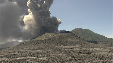 Active volcano steaming, smoke. Caldera. Recent lava flows have cooled and solidified around the cone. An eruption probably tore the top of the volcano off and created the caldera. Ash.