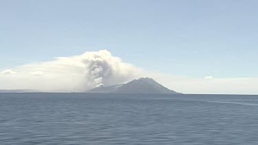 Wideshot Rabaul Volcano Papua New Guinea. From sea. Volcanic Eruption steam and smoke rising.