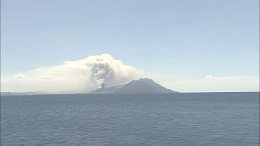 Wideshot Rabaul Volcano Papua New Guinea. From sea. Volcanic Eruption steam and smoke rising.