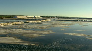 Salt mining and salt processing, manufacture Cheetham salt. Great Australian Bight. Triangular mountains of salt scrapped up. Salt produced by evaporation. See evaporation pans.