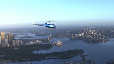 Sydney at sunrise. Helicopter and early morning light. Very blue light and metallic blue helicopter. Opera House, Circular Quay, Harbour Bridge, North Sydney