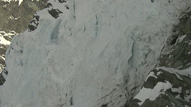 Blue glacial ice on steep mountain slope.