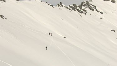 Three People snow boarding down white virgin snow field slope