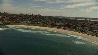Aerial Bondi Beach, Sydney zoom out to see Sydney city, Harbour Bridge and harbour in background