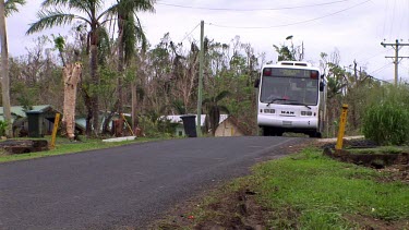 Bus driving along rural town road in tropical Queensland. Palm trees on side of the road