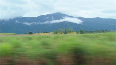 Tracking shot, landscape of Tropical North Queensland. Farms and mountain with clouds.