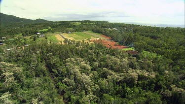 Aerial over rainforest near Mission Beach, Queensland. Shows that much of the area has been cleared for farming and roads. Also shows how much of the forest was damaged and destroyed by cyclone