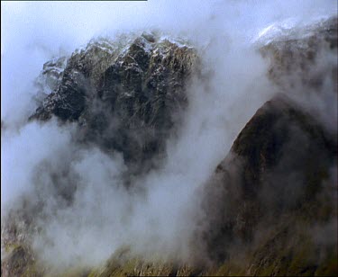 Misty, Smokey, wispy clouds surround mountain peaks