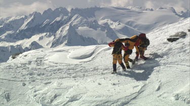 Aerial of Mount Everest: Two climber holding and supporting other climber. Stop & view surroundings