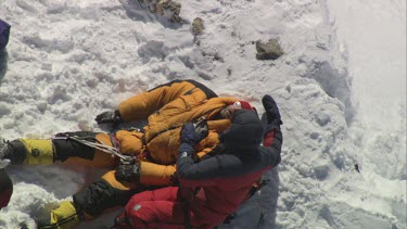 Aerial of Mount Everest:  Climbers looking after troubled climber. Another climber places a oxgen mask on troubled climber and sits him up.