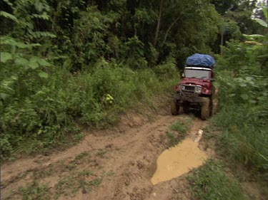Sumatra forest four-wheel drive 4x4 driving over river in forest. Getting stuck in the mud. Road is bogged down with mud. Tires spinning