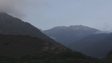 Time lapse of clouds around the Toubkal mountain, Morocco. Day to night. Fades to darkness black
