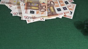 Dice rolling against Green background with 50 euros Bills, slow motion