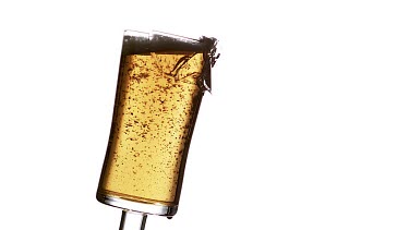 Glass of Beer Breaking and Splashing against White Background, Slow motion