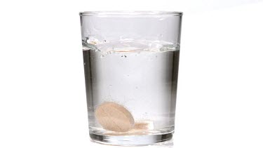 Tablets Dissolving in a Glass of Water against White Background, Slow Motion