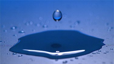Drop of Water falling into Water against Blue background, Slow motion