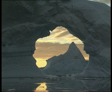 Past large archway in ice framing ice mountain in background