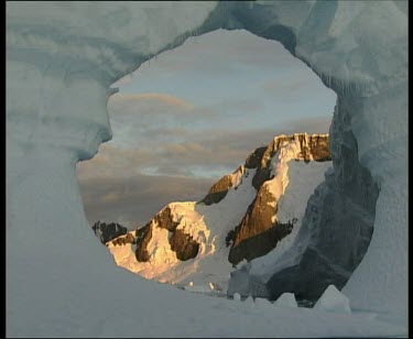Past large archway in ice framing ice mountain in background