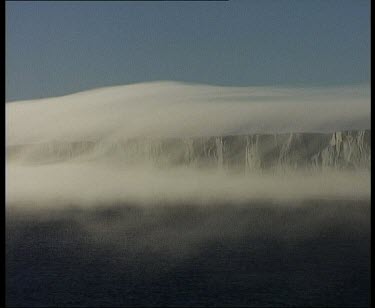 Thick layer of very low cloud over blowing over cliffs and over sea. Looks like tablecloth.