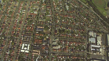 Very high shot of Suburbia, houses, regular straight lines of roads and swirling spaghetti junctions of highways and railways