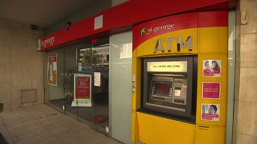 Bank automatic teller machine. ATM woman walks into shot to draw money.