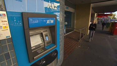 Bank automatic teller machine. ATM woman walks into shot to draw money. Close up, inserting card into cash machine. Inserting numbers and touching touch screen, removing cash from machine. Types in $1...